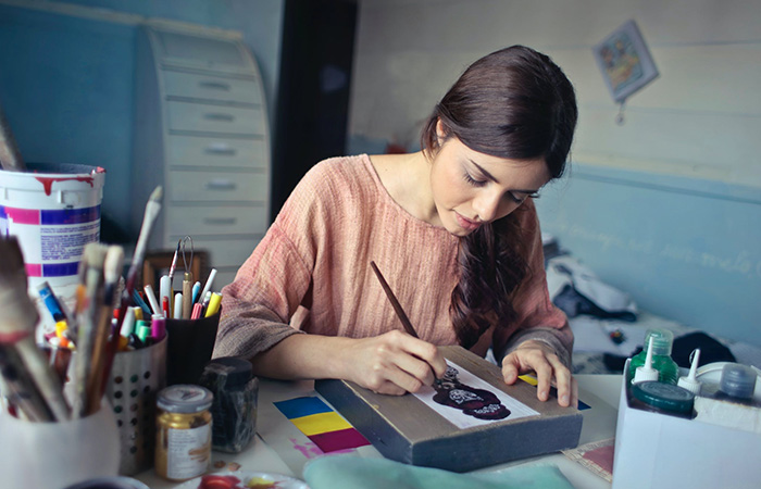 Selvstændig yngre kvindelig kunstner kvinde maler med pensel i sit kunst atelier